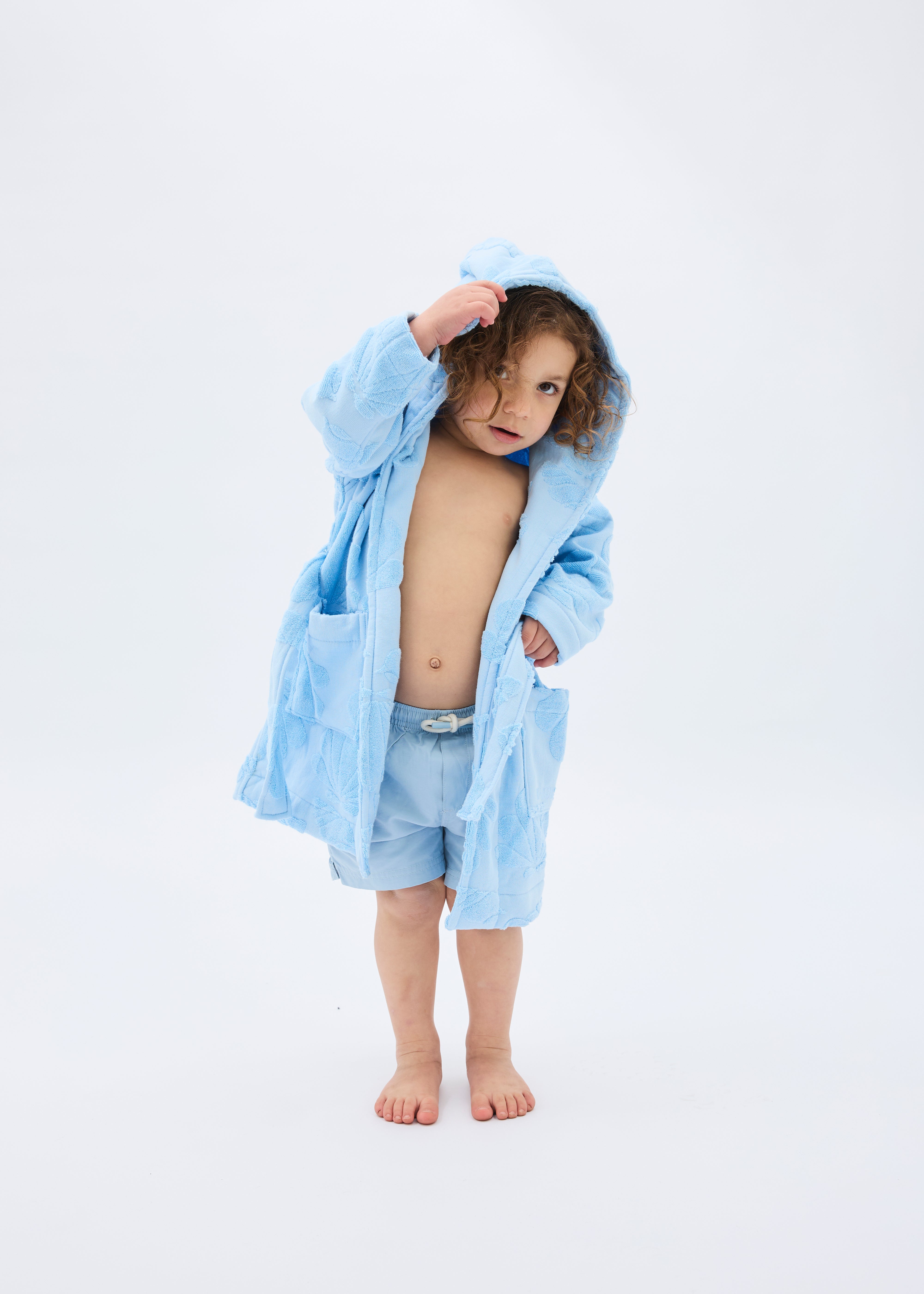 Child wearing a light blue robe on a white background